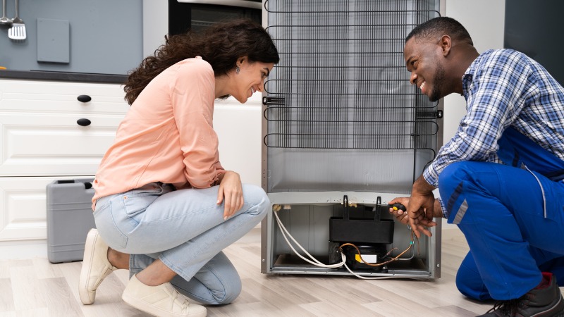 vrouw en mannen zitten gehurkt bij de achterkant van een koelkast